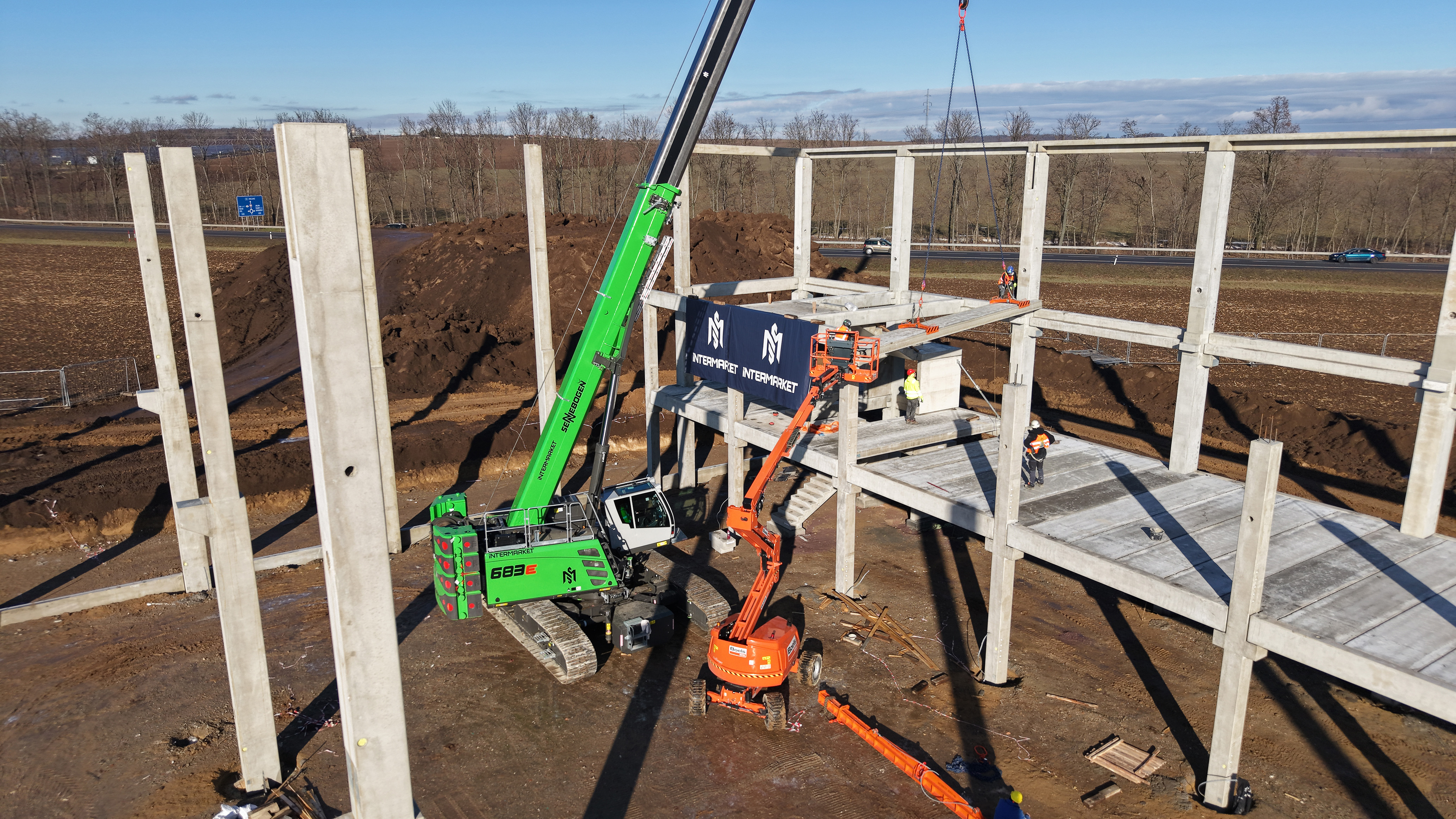 Assembly of the prefabricated concrete structure in the AVENTIN Dyje Industrial Park – the SENNEBOGEN 683 E performs key lifting and positioning tasks. 