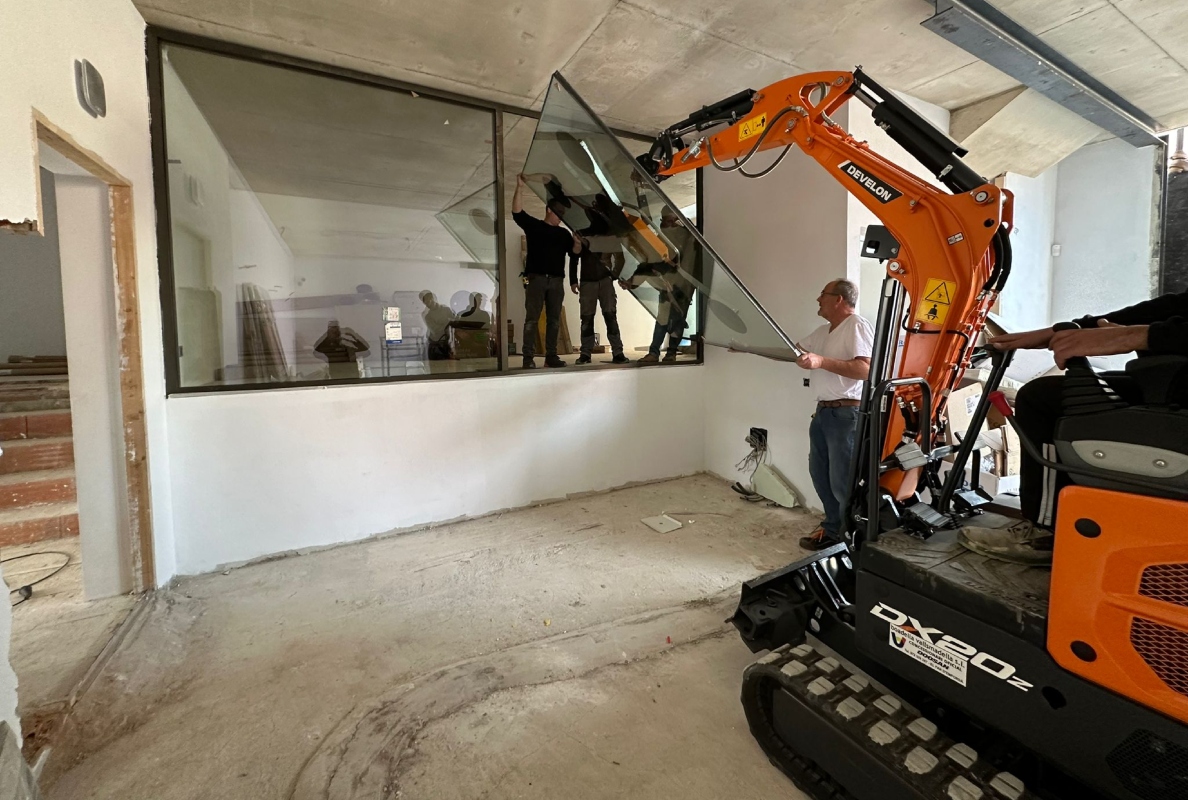 Develon Mini-Excavator Used to Install Panes of Glass in Home