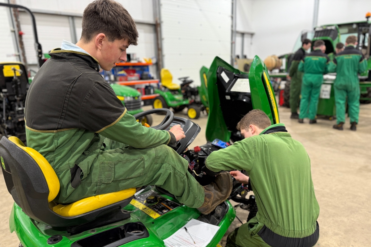 Turf-tech apprentices on a piece of mowing equipment