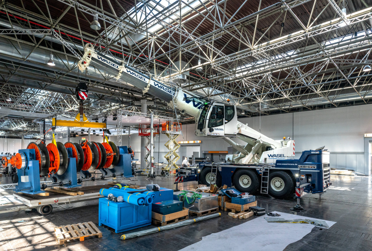 XXL exhibition stand construction: In some cases, large exhibits had to be moved precisely by the Liebherr LTC 1050-3.1 via the telescopic extension. Due to the low ceiling height, positioning the load via the boom inclination was almost impossible.