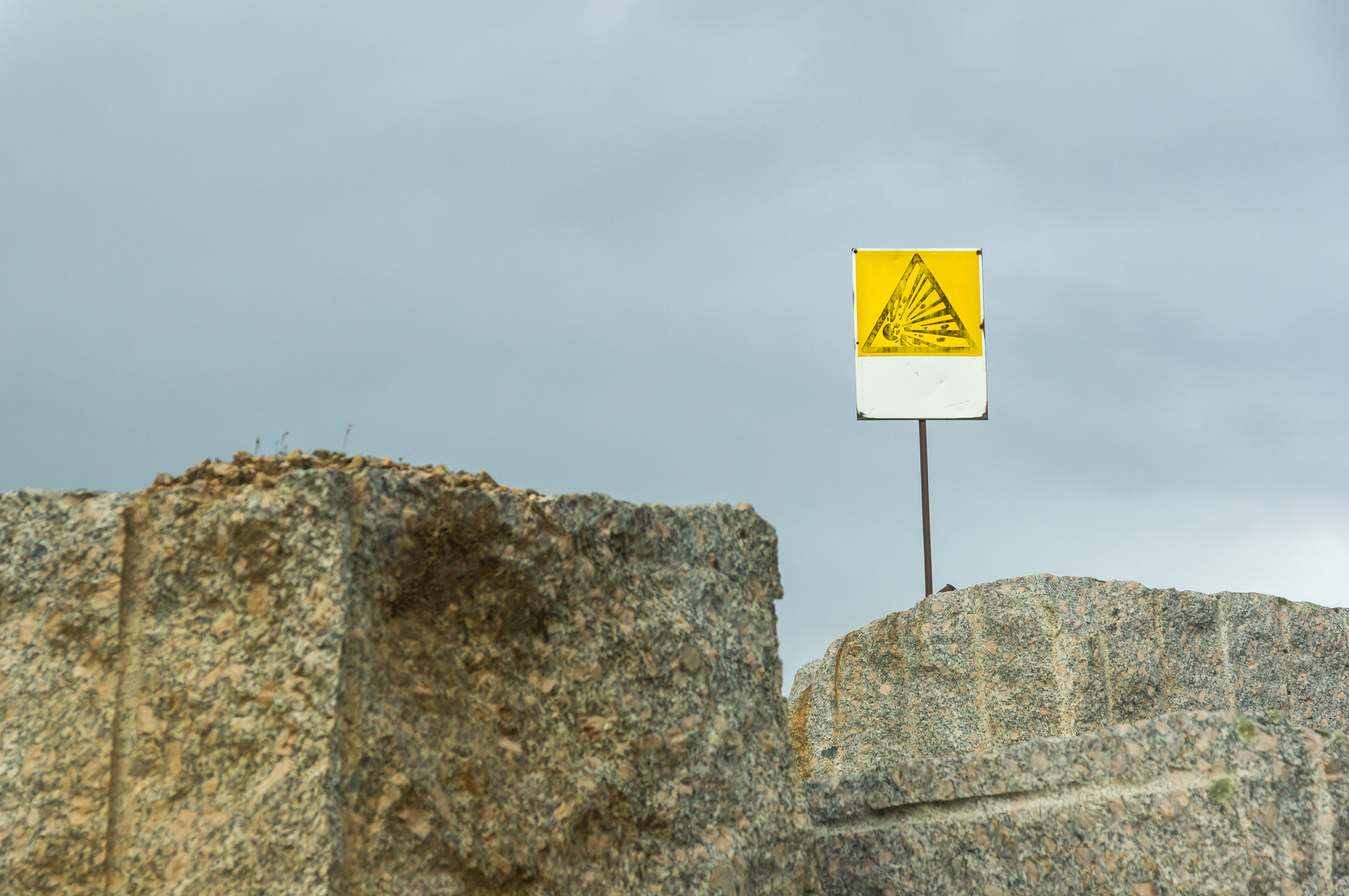 Excavation zone marked with a warning sign for ongoing rock blasting.