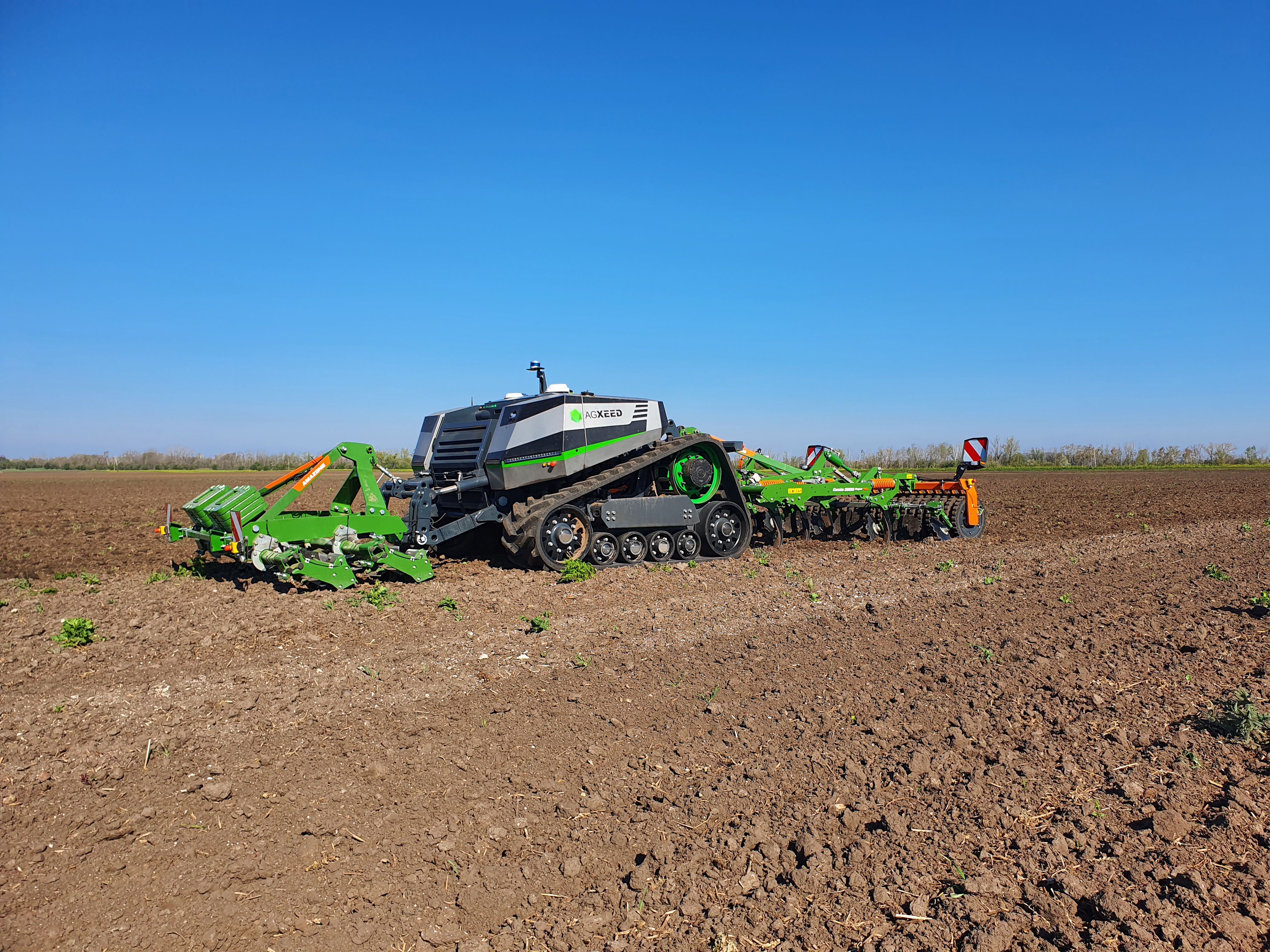 The tracked AgXeed AgBot with 3 m AMAZONE Cenio mounted cultivator and front-mounted knife roller