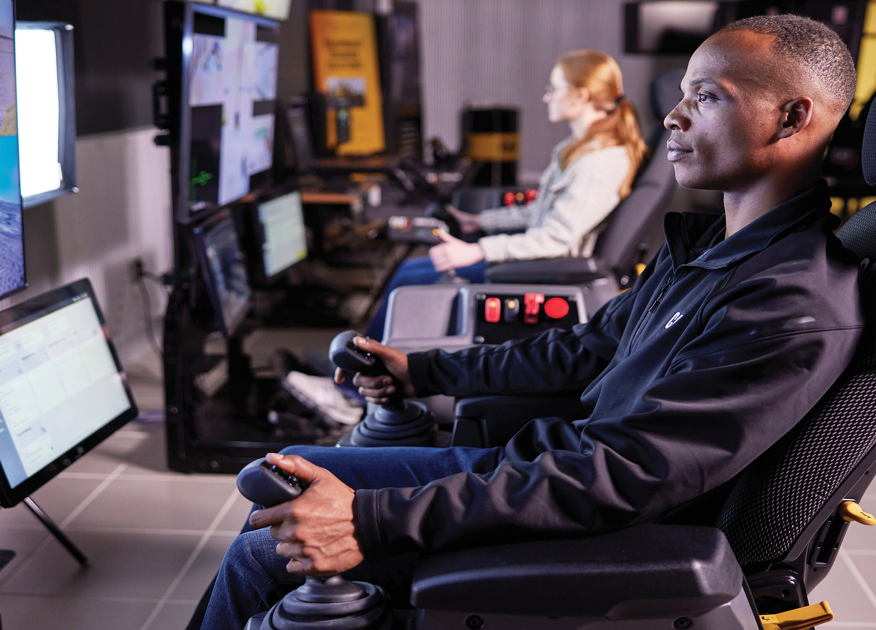 Cat® Command Stations in an office environment being used to remotely control excavators.