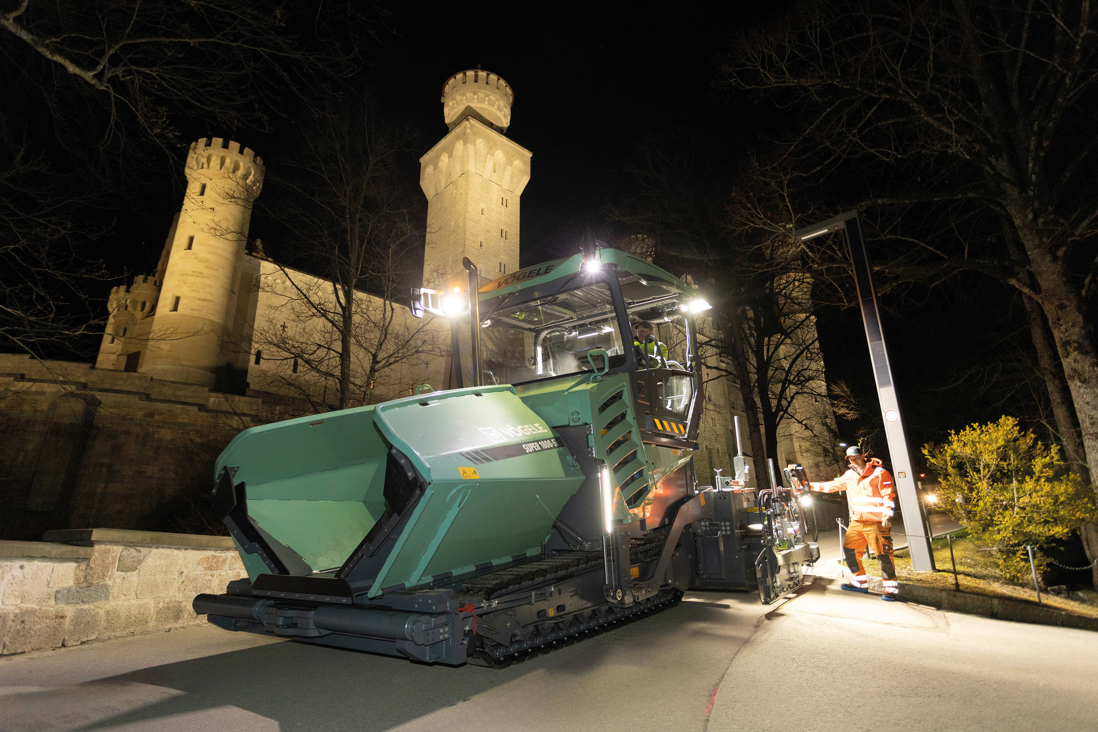 Night-time pavement rehabilitation of the access road: The SUPER 1800-5 X against the backdrop of the Bavarian royal castle Neuschwanstein.