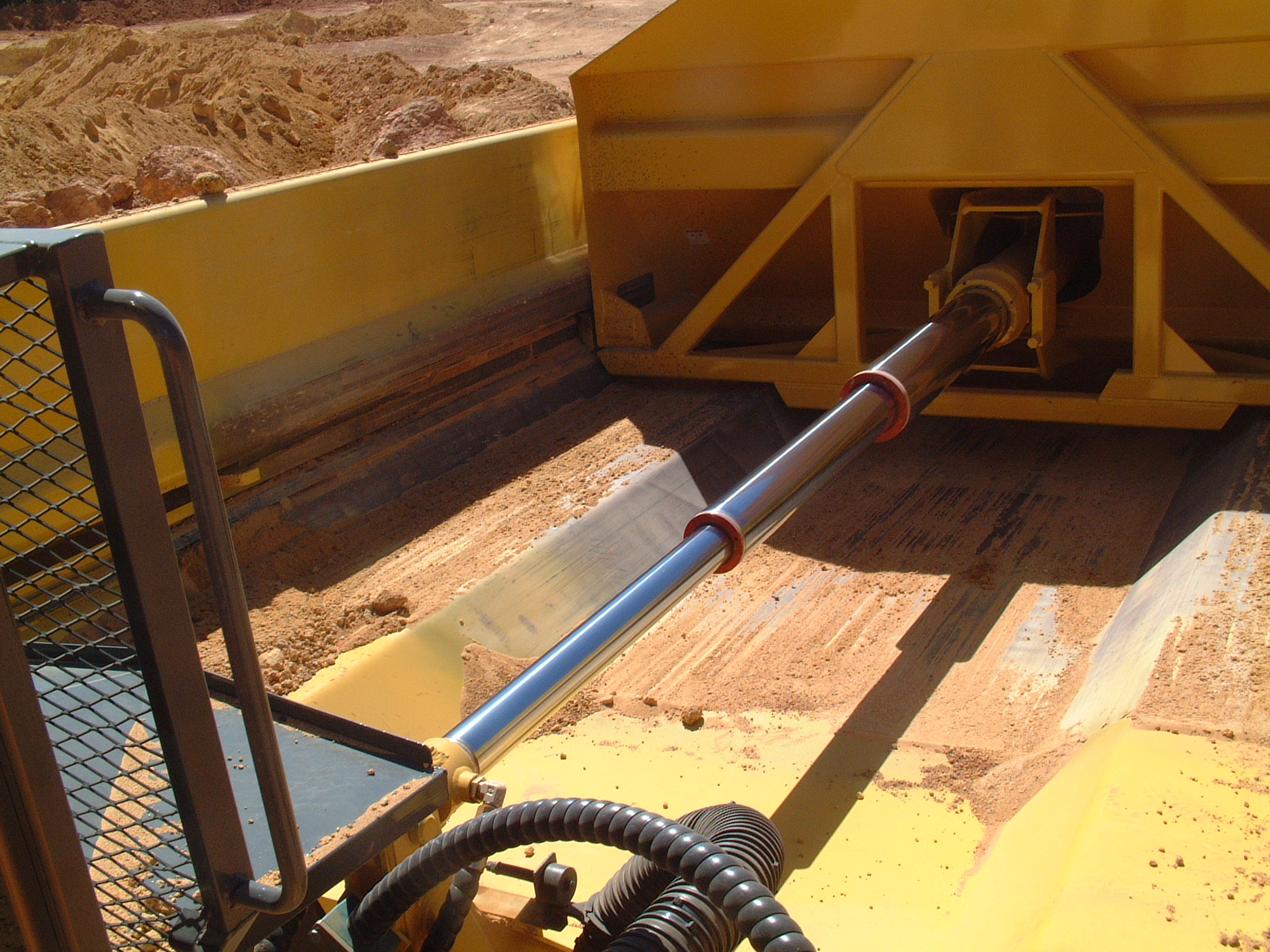 A single hydraulic cylinder operates both the ejector blade and the rear tailgate mechanism.