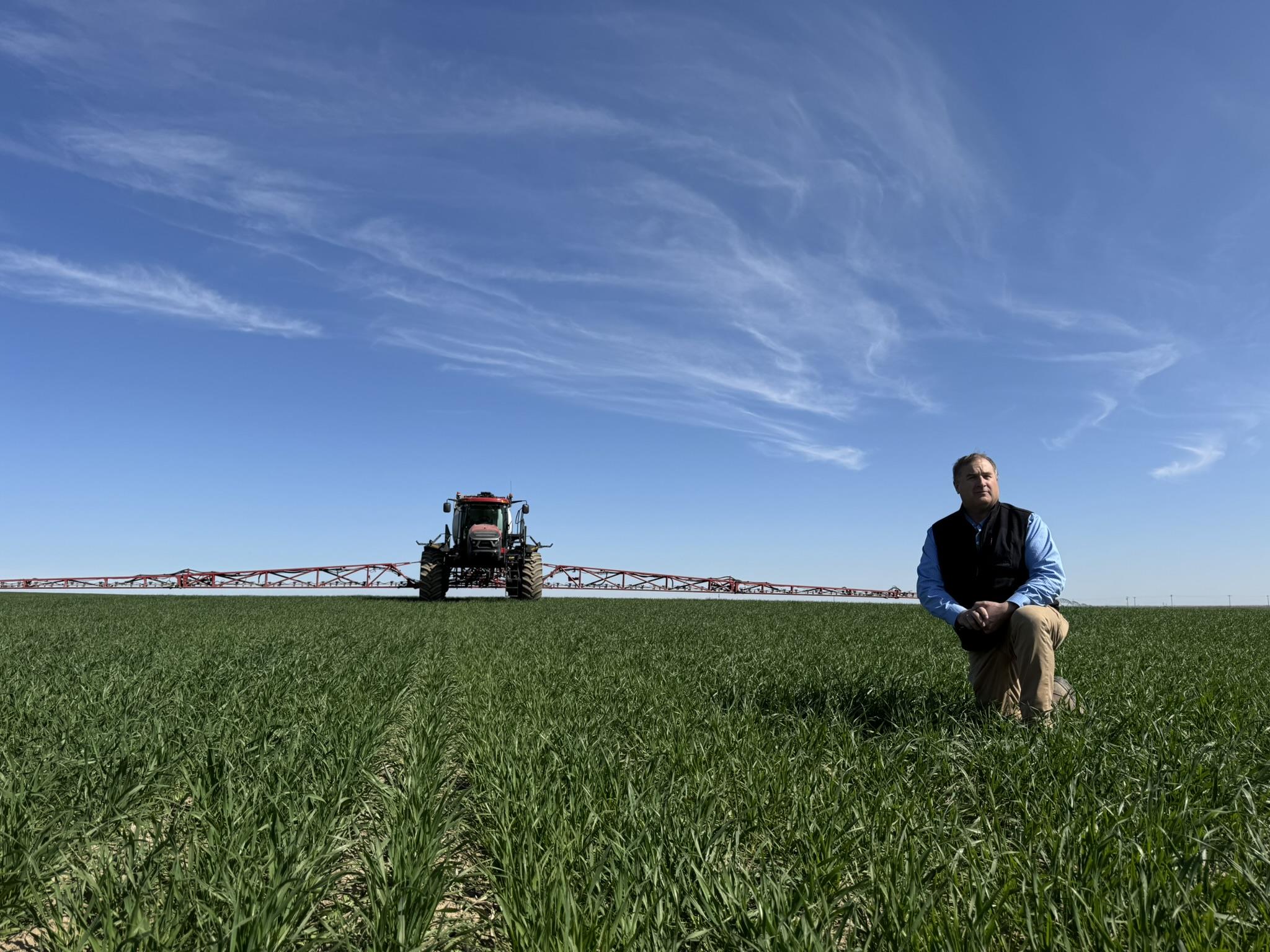 A man in a field with a Case IH sprayer using SenseApply Technology