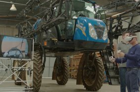 A CNH employee conducts operator training for a New Holland sprayer using a virtual reality headset and controls