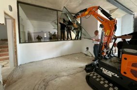 Develon Mini-Excavator Used to Install Panes of Glass in Home