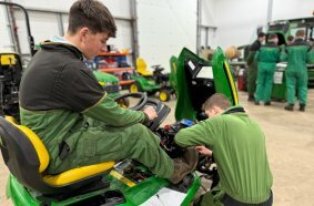 Turf-tech apprentices on a piece of mowing equipment