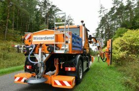 Unimog implement carrier with front mower, hedge trimmer, and spreader