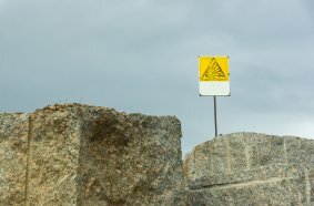 Excavation zone marked with a warning sign for ongoing rock blasting.
