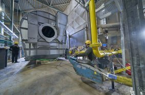 Sliding the dryer drum into position inside the emission housing of the Benninghoven asphalt mixing plant with the aid of a specially constructed jig. 