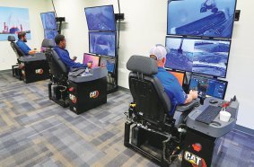 Cat® Command Stations being used to remotely control excavators at a river terminal to unload barges and ship cargo holds.