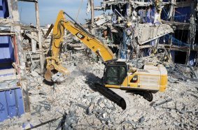 Cat® excavator working at a building demolition project by remote control.