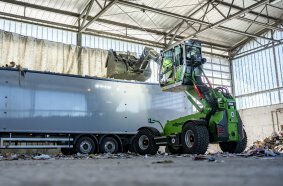 The SENNEBOGEN 340 G effortlessly loads waste into a truck with its telescopic arm.