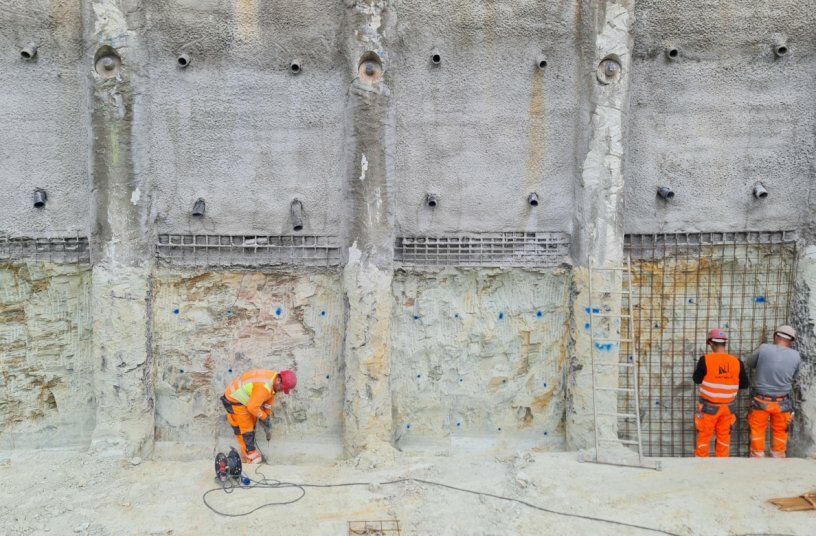 Layer by layer, the areas of quartzite rock between the bored piles are exposed. After lining with steel mesh, shotcrete is applied. The amount of shotcrete used is kept to a minimum.<br>IMAGE SOURCE: KEMROC Spezialmaschinen GmbH