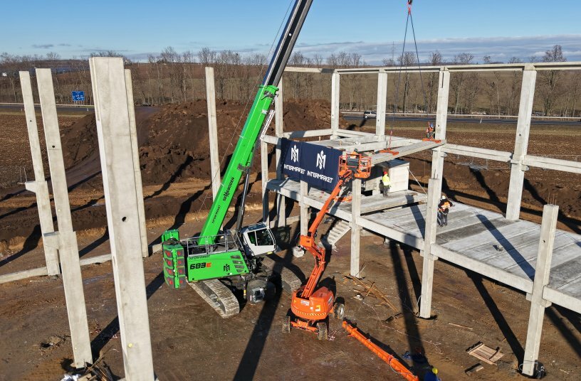 Assembly of the prefabricated concrete structure in the AVENTIN Dyje Industrial Park – the SENNEBOGEN 683 E performs key lifting and positioning tasks. <br>IMAGE SOURCE: SENNEBOGEN Maschinenfabrik GmbH