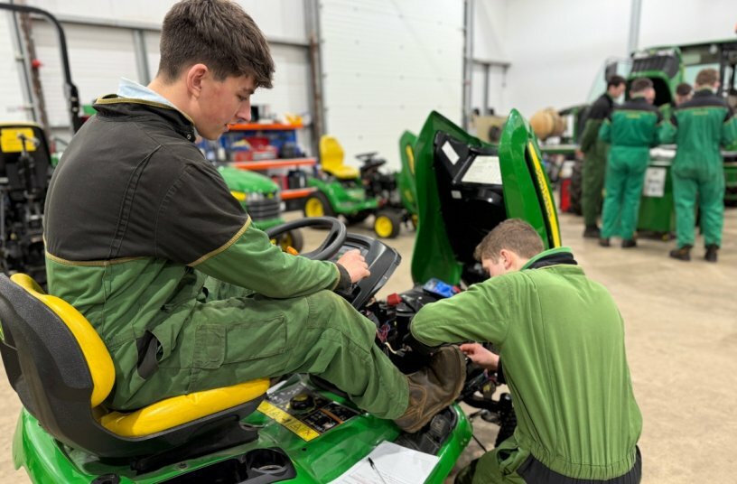 Turf-tech apprentices on a piece of mowing equipment<br>IMAGE SOURCE: John Deere