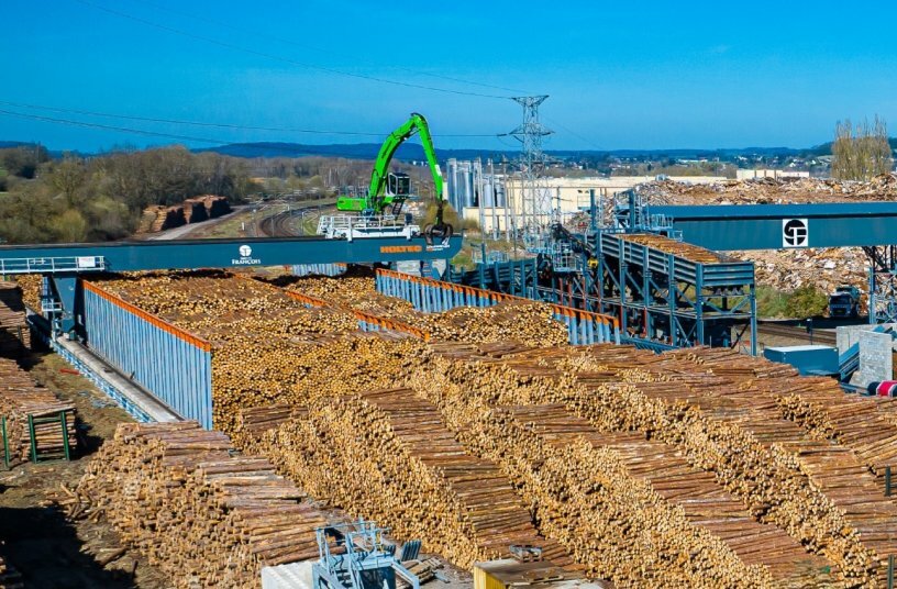 Since the SENNEBOGEN 840 E moves along the HOLTEC plant, travel lanes between the log piles are eliminated completely. Despite the compact space conditions, every area of the log yard remains fully accessible.<br>IMAGE SOURCE: SENNEBOGEN Maschinenfabrik GmbH
