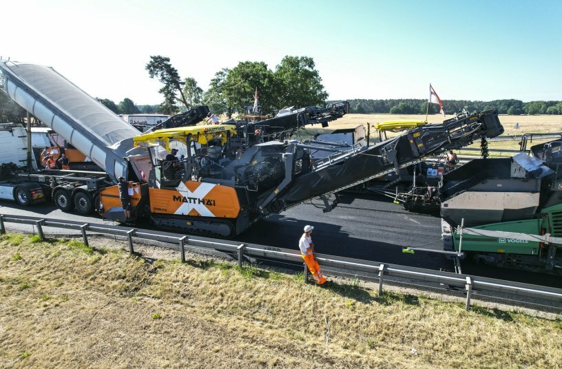 In each train, a high-performance MT 3000-3i Offset material feeder received the material for the binder and surface courses and conveyed it directly to the material hopper or the transfer module of the following SUPER 2100-3i IP paver at precisely timed intervals.<br>IMAGE SOURCE: WIRTGEN GROUP