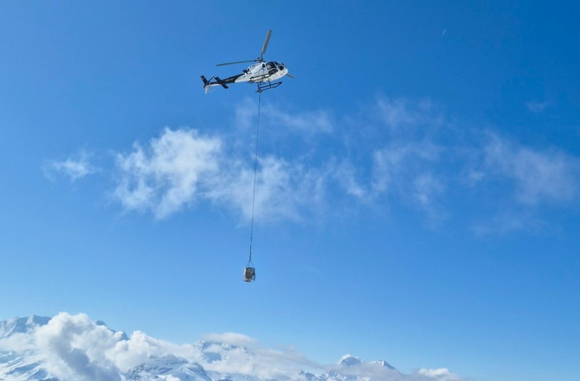 A spectacular material feeding method. A helicopter offloaded fresh, hot asphalt mix to the MINI 500 every four minutes to keep it constantly supplied with sufficient material for continuous paving.<br>IMAGE SOURCE: WIRTGEN GROUP