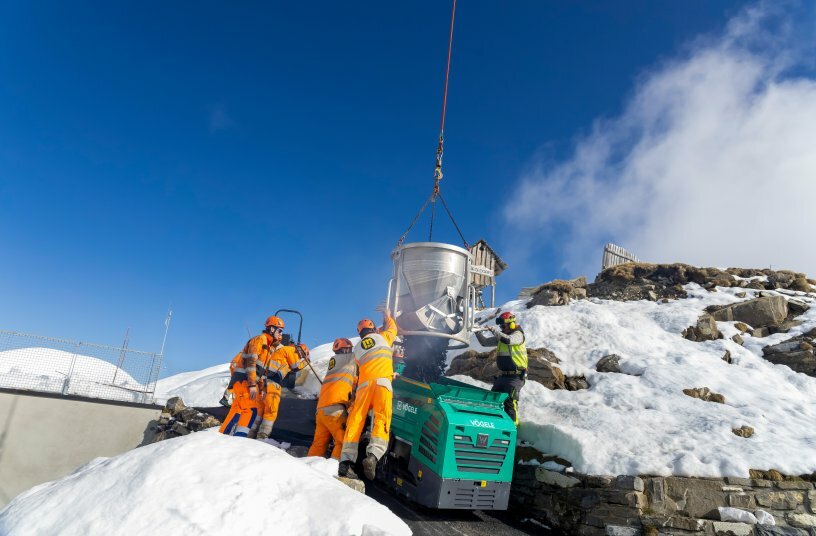 The helicopter transferred the mix directly into the material hopper of the Vögele paver.<br>IMAGE SOURCE: WIRTGEN GROUP