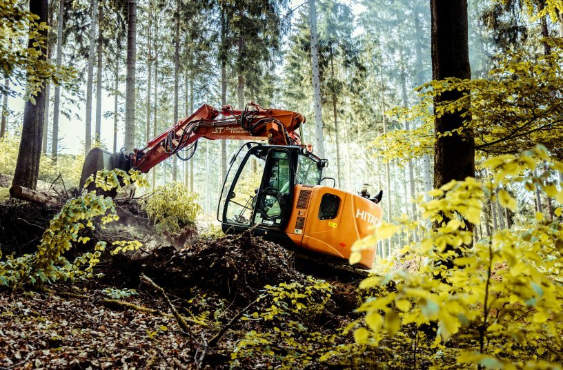 Der Hitachi ZX135US manövriert präzise zwischen den hohen Bäumen und räumt die Trails frei.<br>IMAGE SOURCE: wyynot GmbH; Kiesel GmbH