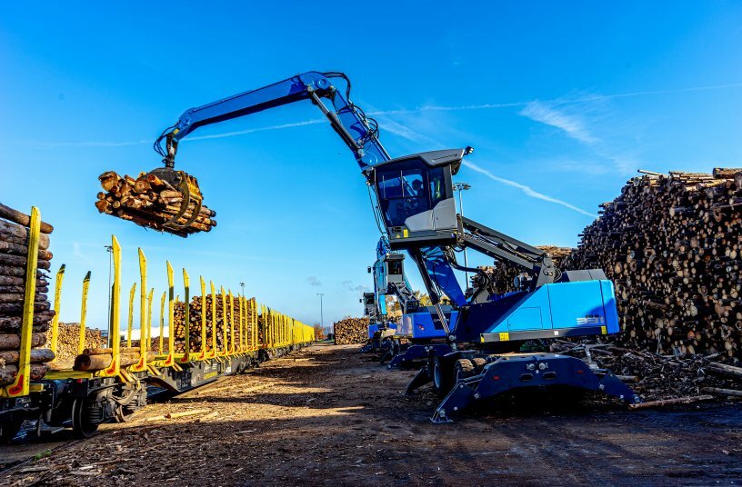 Im Taktschlag: Drei Fuchs MHL331F Umschlagbagger bei der Verladung von Holz auf Waggons.<br>BILDQUELLE: Kiesel GmbH