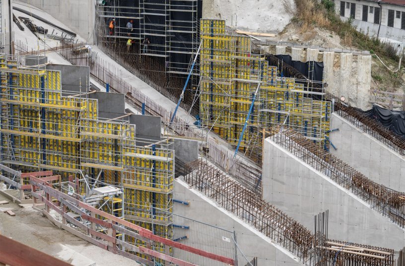 The water plunges down through three pressure pipelines, each with a 10.4 x 12.75m cross-section and a gradient of 26.5 degrees. Then the water is directed towards the three Kaplan turbines. Framed formwork Framax Xlife was used to build the steeply inclined walls. <br> Image source: Doka