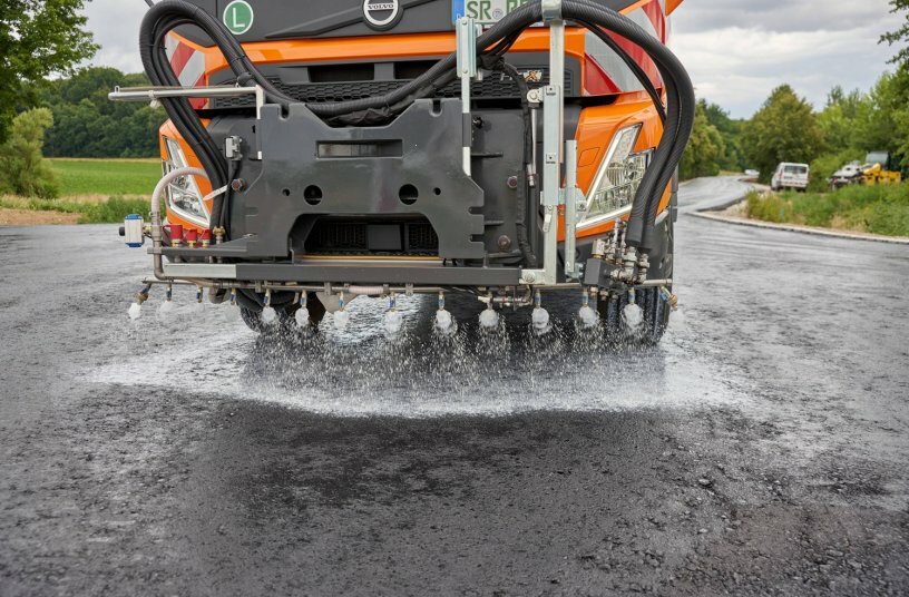 Frontseitig angebrachte Spritzdüsen können bedarfsweise Kalkmilch als „Schutzschicht“ auf die Bitumenemulsion verteilen.<br>BILDQUELLE: schäfer-technic GmbH