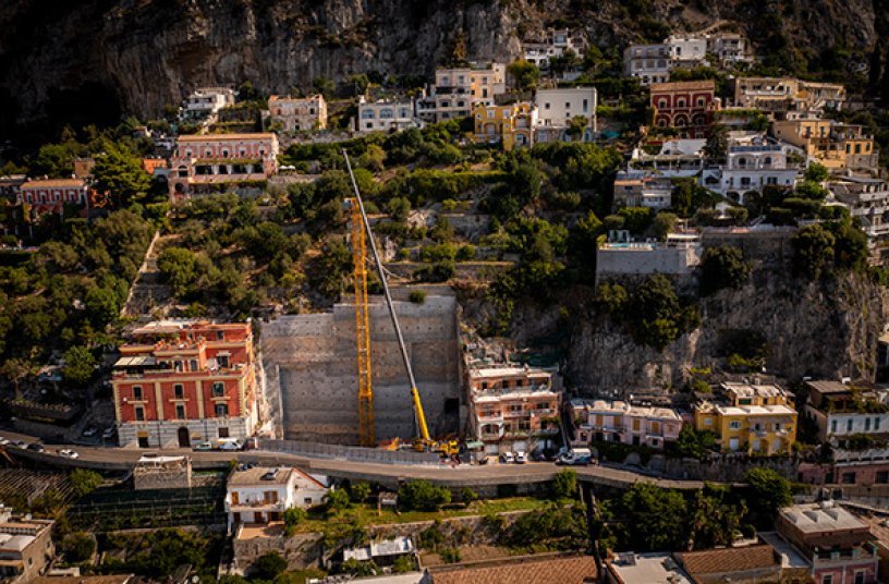 A Grove GMK4100L-1 all-terrain crane is assembling the Potain MDT 189 tower crane to help construct a multi-story parking lot and elevator into the rockface <br> Image source: THE MANITOWOC COMPANY, INC.