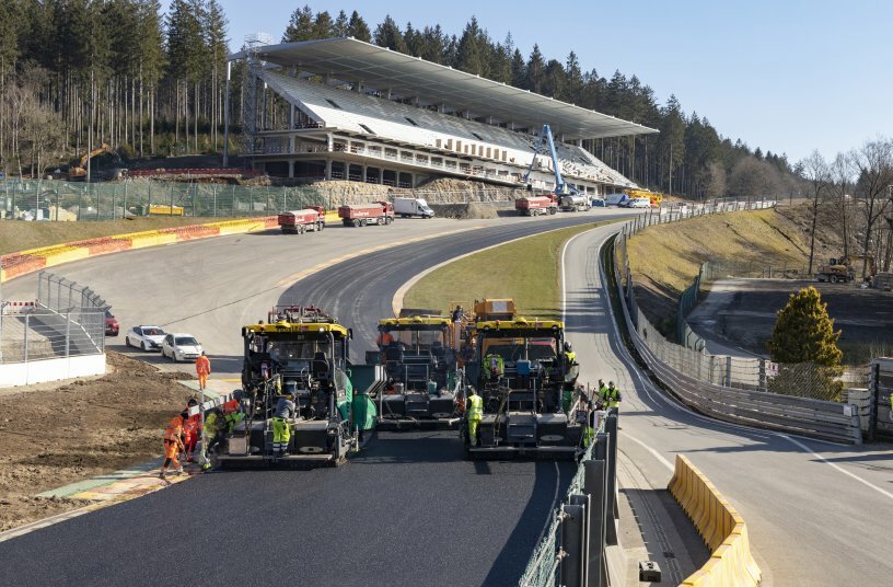 The legendary Raidillon sweeping Formula 1 corner, with its 20% gradient, is one of the great challenges for the paving operation. The new spectator stand at the top of the hill.<br>IMAGE SOURCE: WIRTGEN GROUP