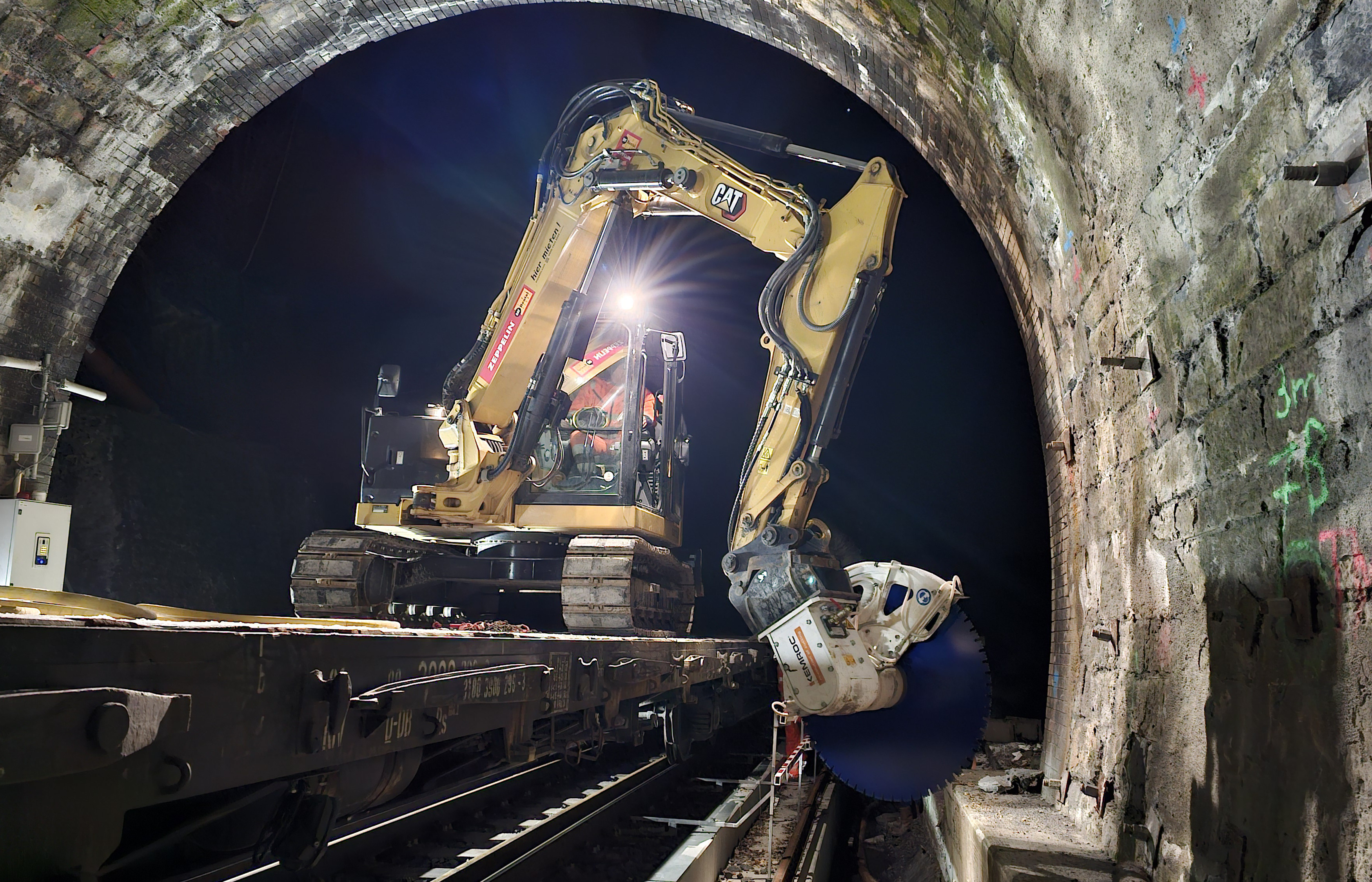 The operator positions the excavator perpendicular to the axis of the tunnel and positions the KEMROC diamond saw on the cable duct at intervals of 150 cm.