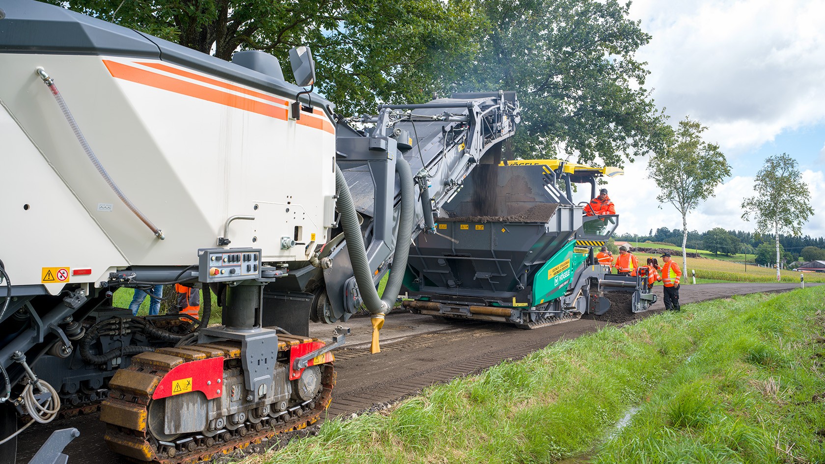   The material is transferred directly to the material hopper of the Vögele SUPER 2100-5i paver and laid down as the train advances.